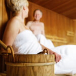 Richtig saunieren: Älteres Ehepaar in weiße Handtücher gehüllt in der Sauna.